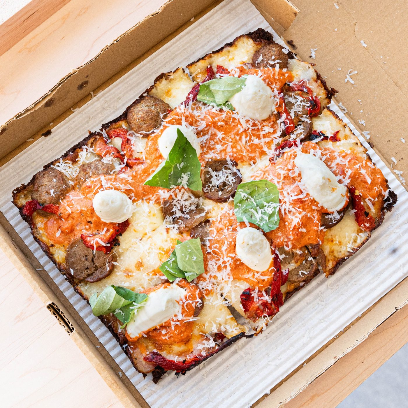 Oh, My Meatball!: Detroit-style pizza with vodka sauce, house-made meatballs, whipped ricotta, roasted peppers, and basil in an open pizza box